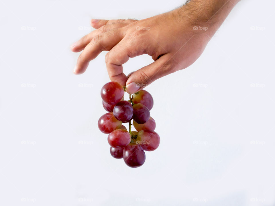 A hand holding a branch of grapes