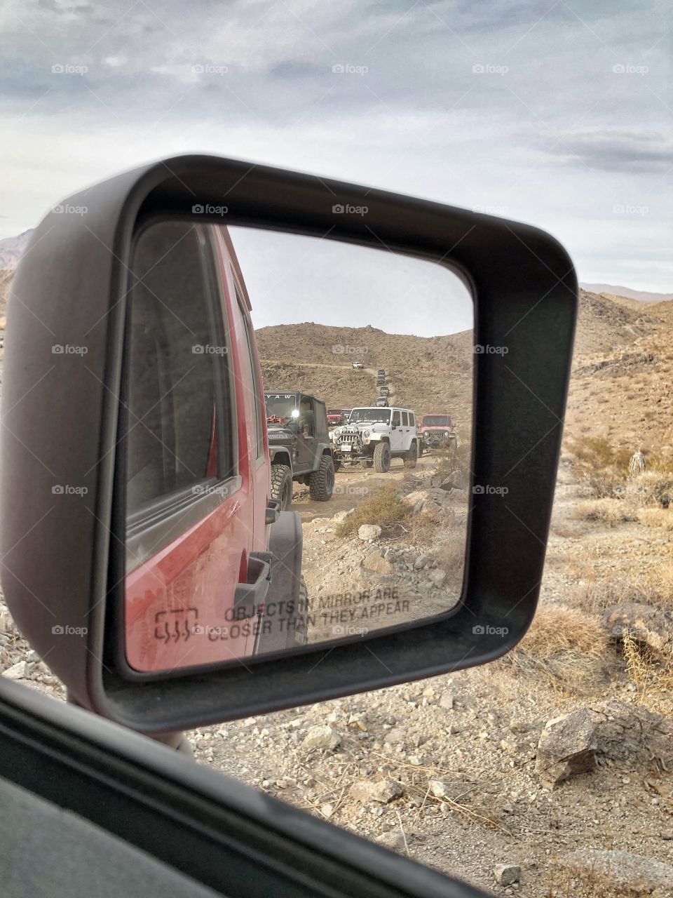 A line of jeeps in a row view through side mirror