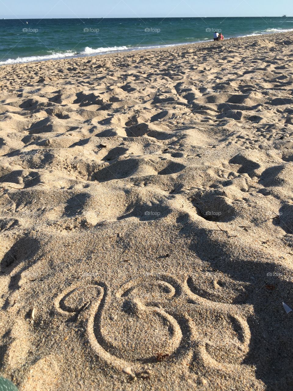 An om in the sand to remind you that the subtle vibrations of the universe vibrate for you. The sand, the water, the earth as a whole, it beats for you. 