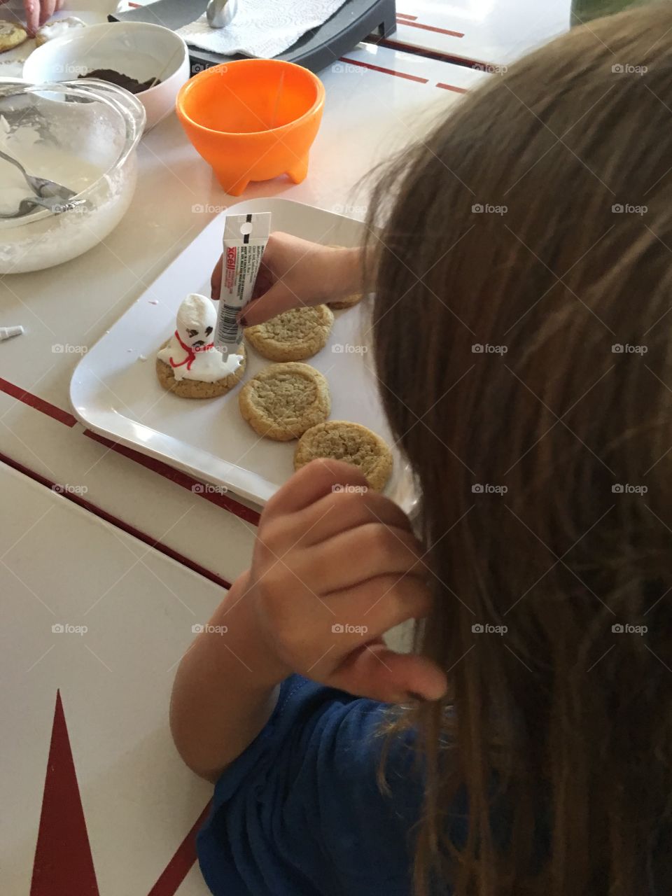 A little girl making melting snowman cookies
