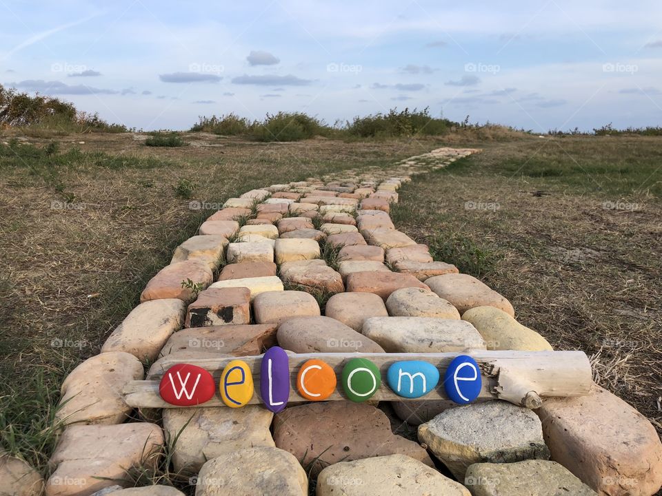 Welcome text with colored stones on a bricks road