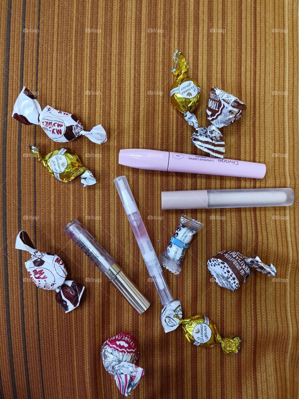 my cosmetics, mascara, oil, lip gloss, concealer, essentials, sweet chocolates, candy wrappers, hair clip.