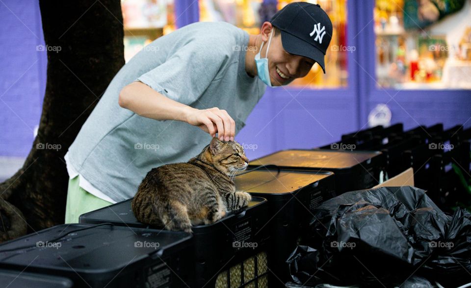 A cat is appreciating love from a random person.