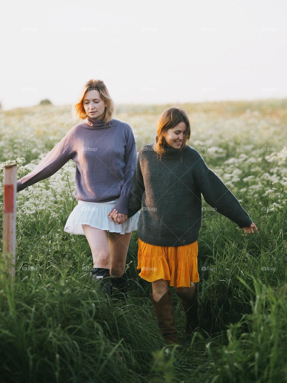 Two young beautiful woman’s walking in field in sunny summer day, portrait of woman