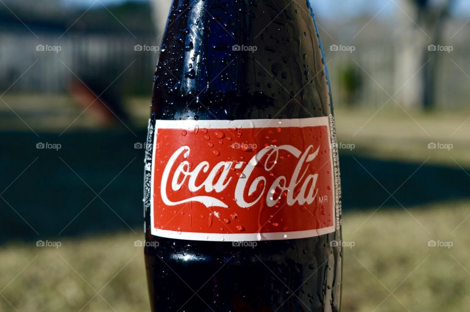 A glass bottle of Coca-Cola with condensation on it