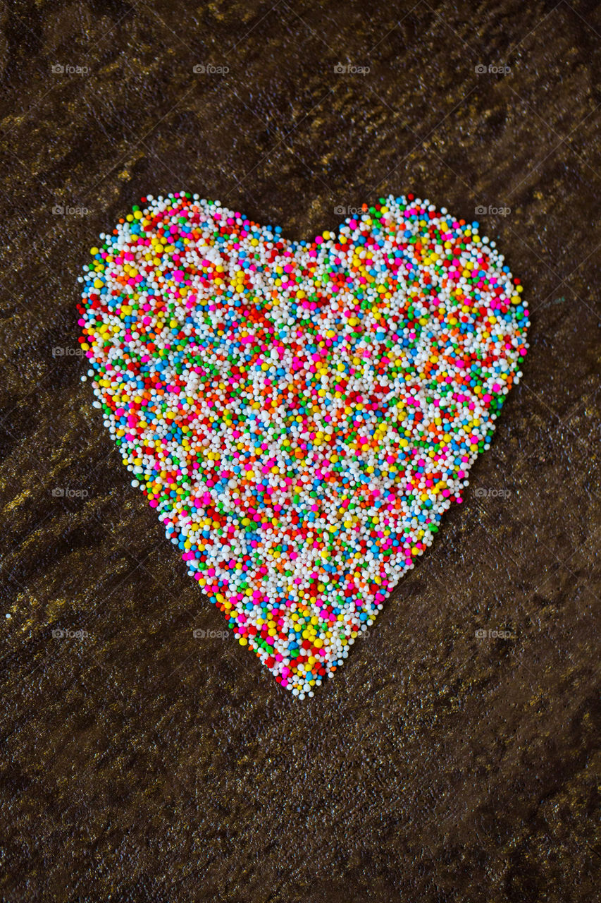 Heart shape made with ice cream sprinkles using different colors. Flat lay heart. Love the bright colours of the cake sprinkles!