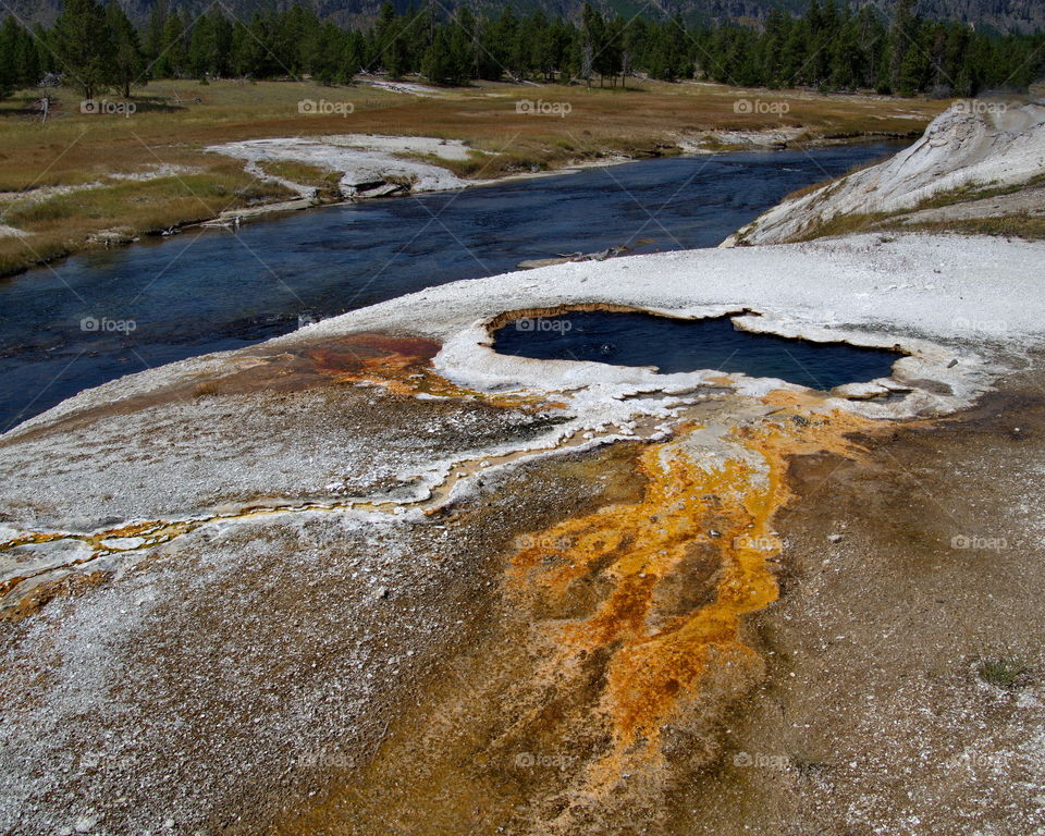 Stunning geology in the unique landscape of Geyser Hill in Yellowstone National Park on a sunny summer day. 