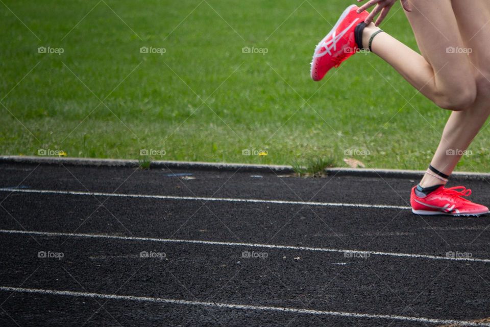 Person running on track in race with red shoes