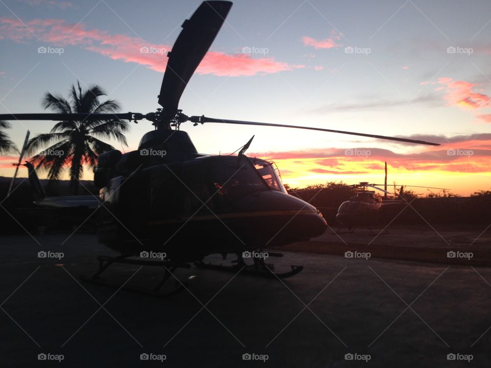 A Bell 412 Helicopter , landed in a courtyard in St Elizabeth, Jamaica with a beautiful country side sunset. 