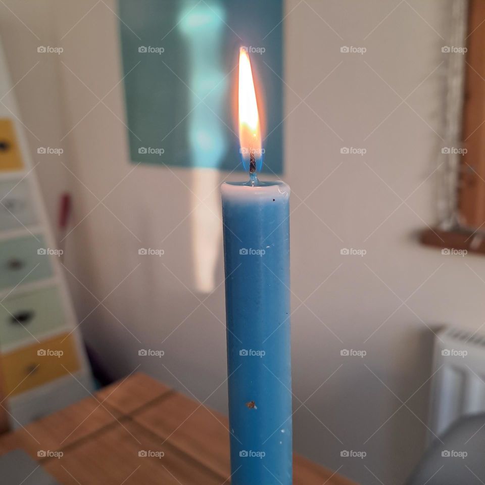 closeup of blue candle on table in foreground with painting and furniture in background