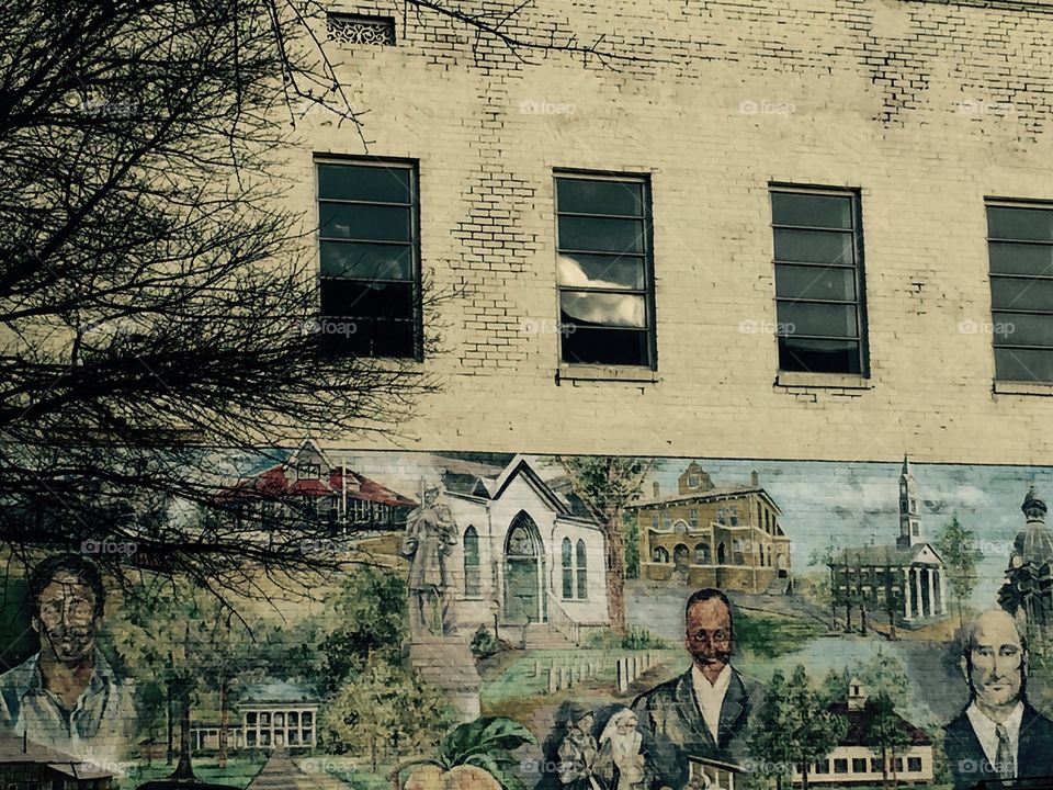 Old brick building with an old mural of history of the town painted on it.