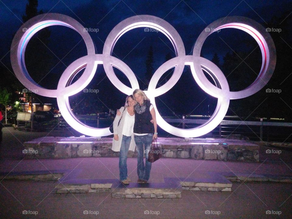 Two women standing in front of Olympic rings, Canada