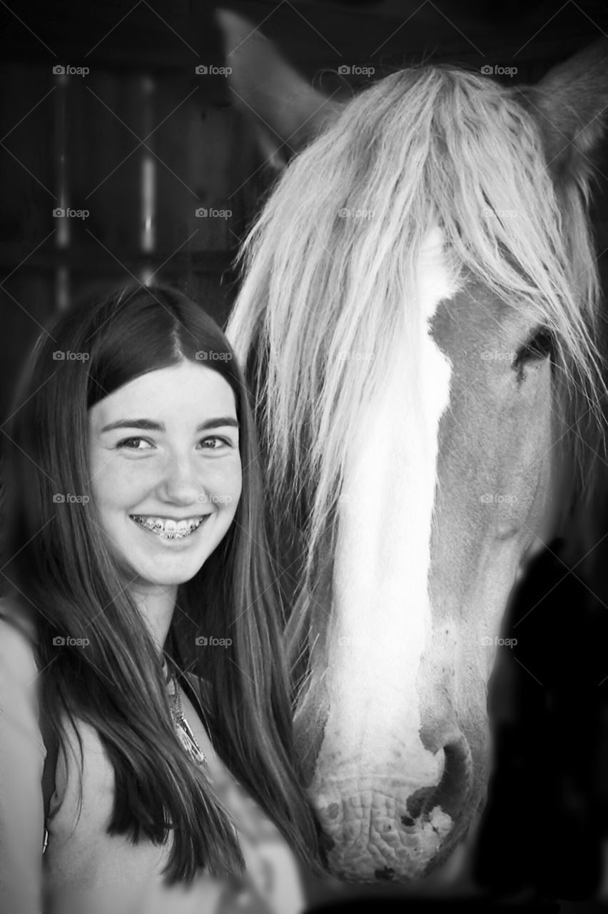 A young girl and her horse bond on a warm spring day at the stables, smiles abound!