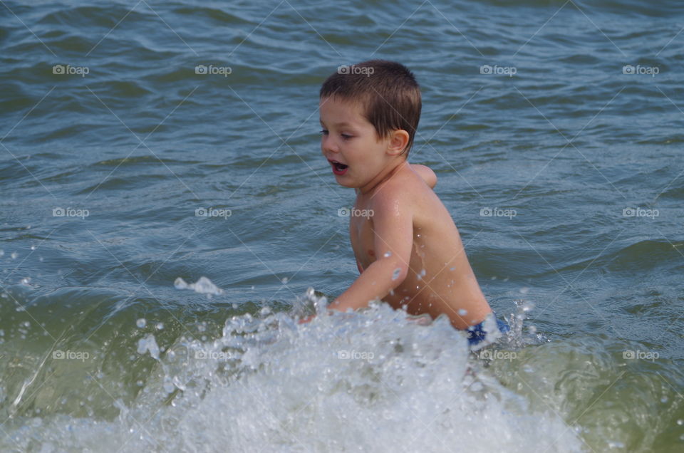 Cute boy splashing water in the sea