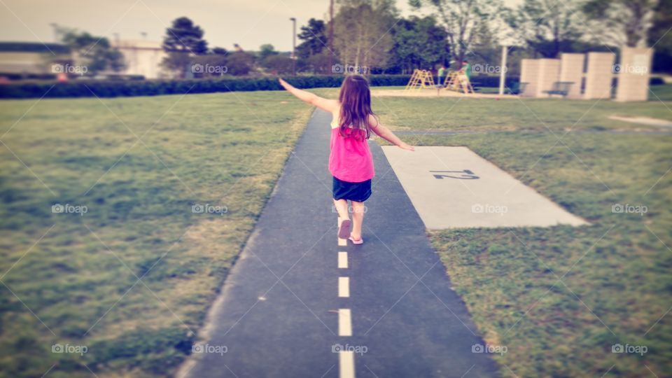 a young girl running with arms spread as wings as if trying to fly