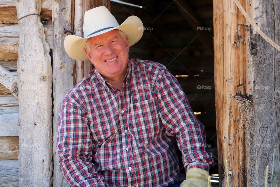 Portrait of senior man in hat against wooden house