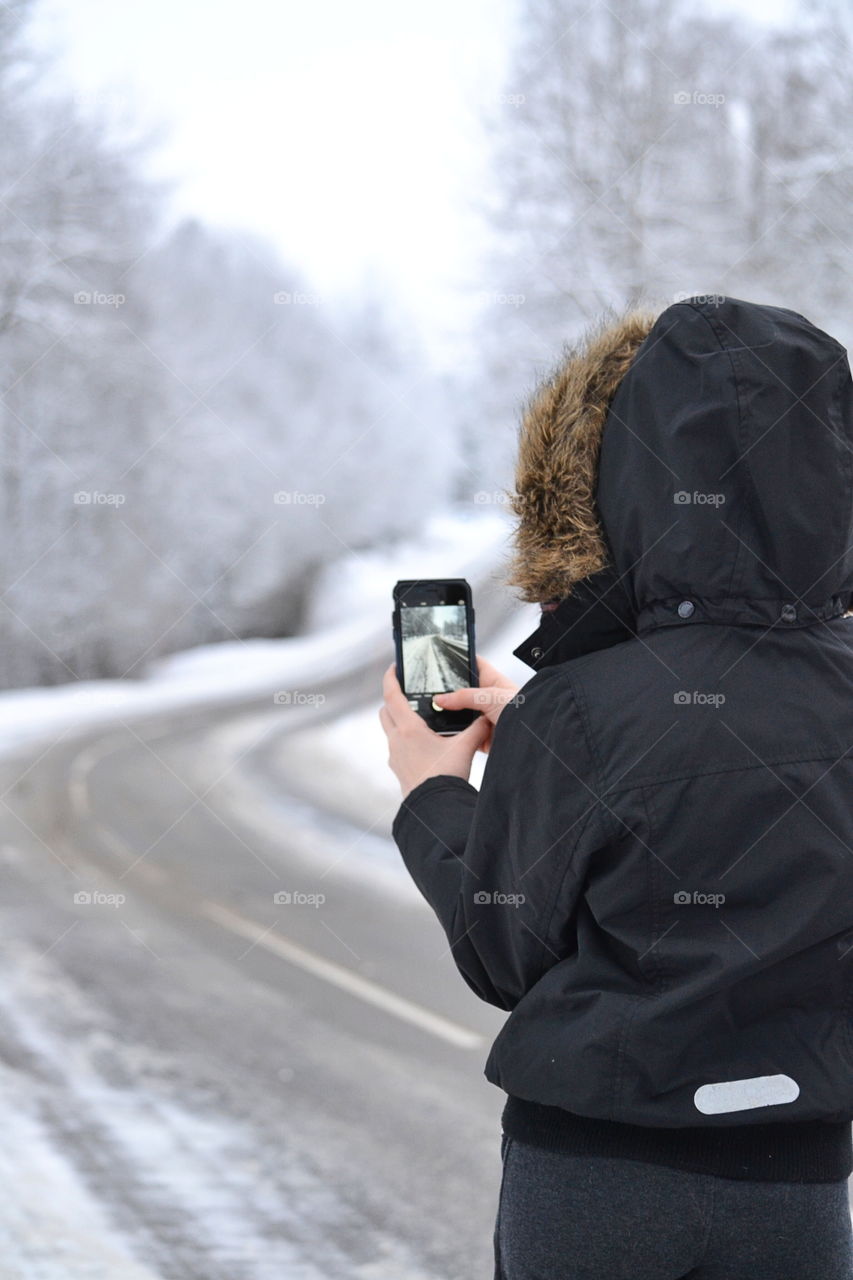 Woman taking a picture of empty road