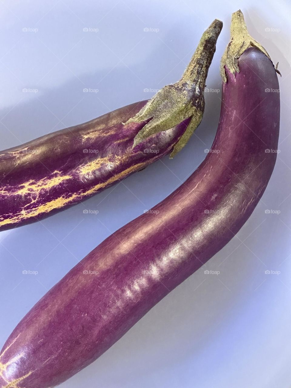 Two Japanese eggplants on a lavender glass plate