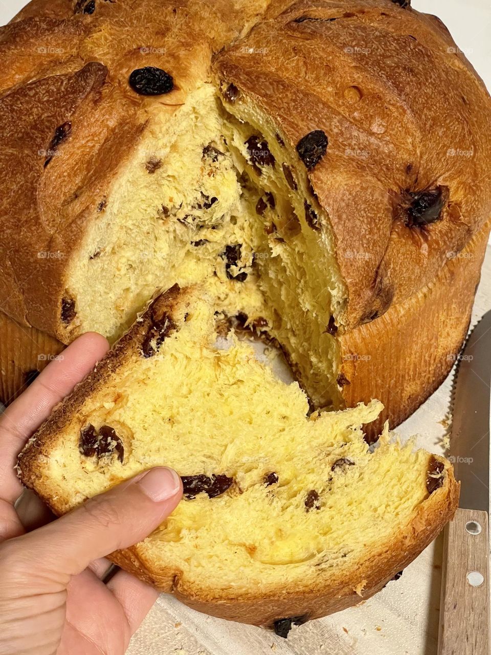 Hand holding a slice of panettone, a typical italian sweet bread prepared for Christmas and New Year 