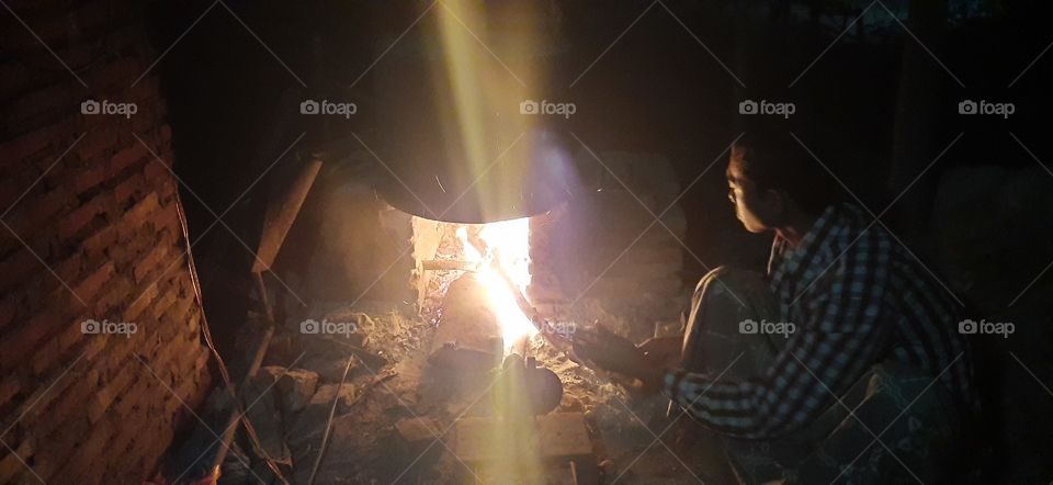 A young man lit a stove to heat water