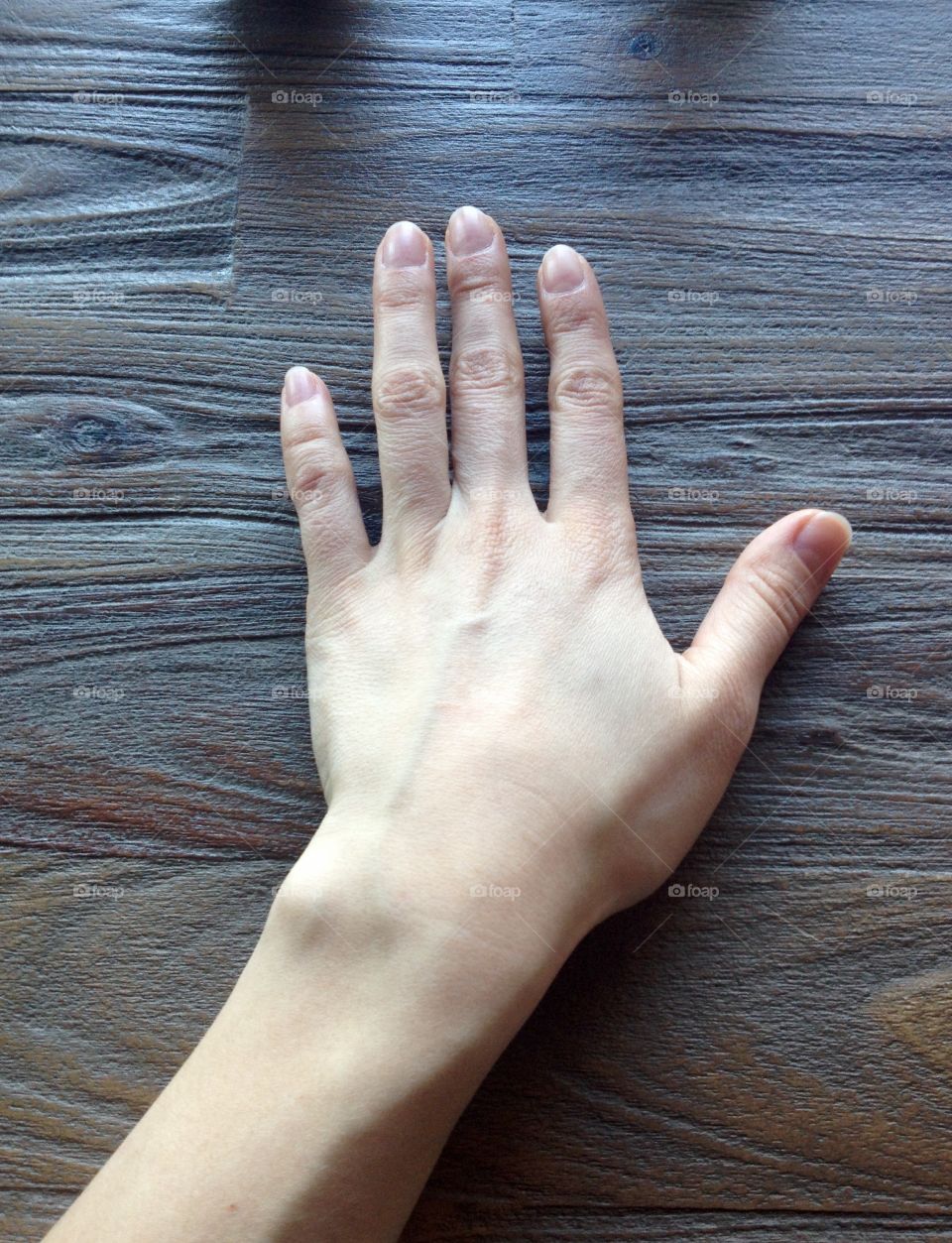 A hand touching a wooden table