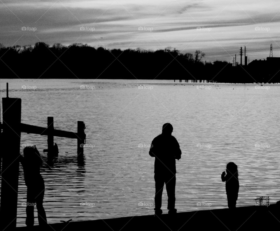A father and his children down at the dock feeding the ducks!