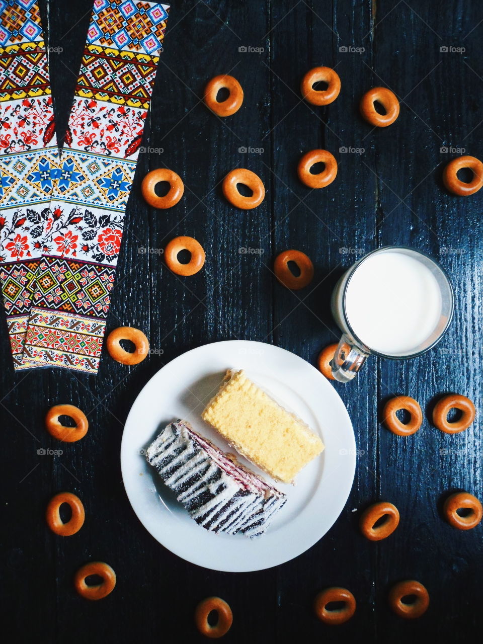 cakes, a cup of milk and bagels on a black background