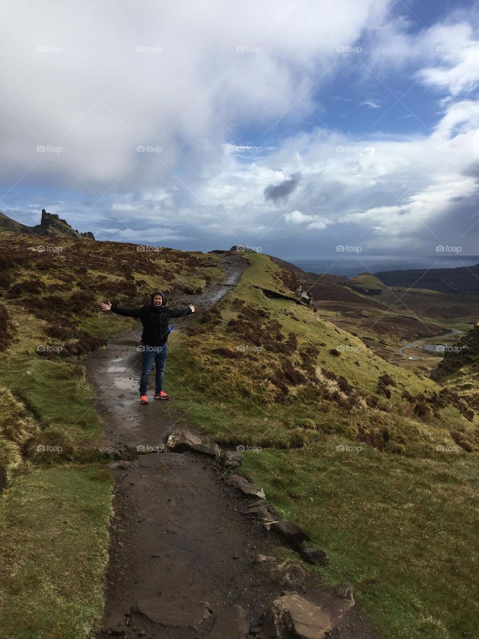 Woman standing with outstretched arms at top of mountains, hiking to the top of mountains, on top of mountain trails, muddy trails on the mountains 