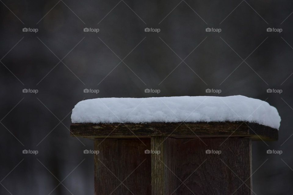 A big layer of snow on wooden seat 