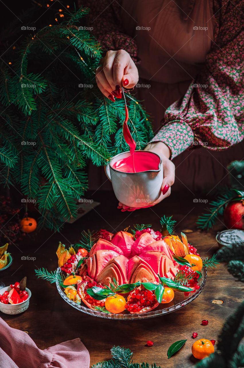 Christmas homebaked magenta color bundt cake decorated with powdered sugar and fresh berries and fruits