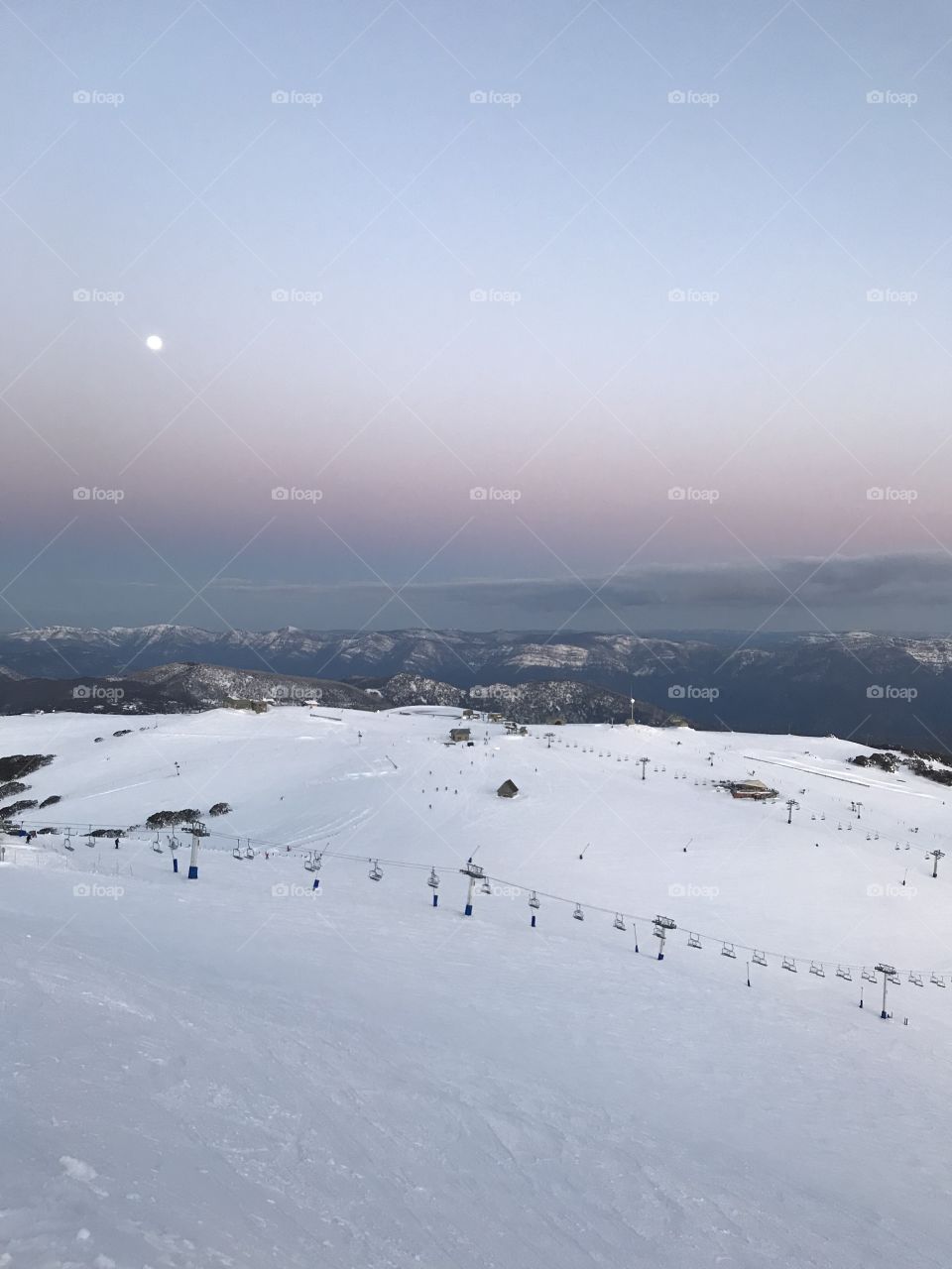 The moon over ski fields at dusk