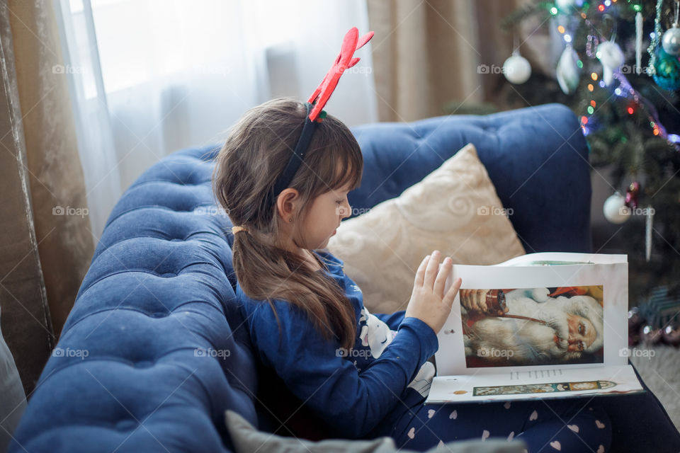 Little sisters reading a book at Christmas time 