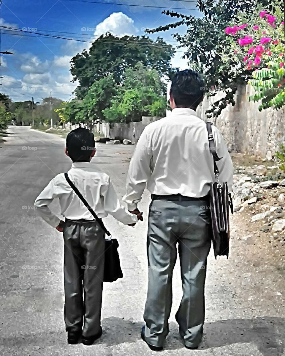 Dad and son holding hands looking at the long road