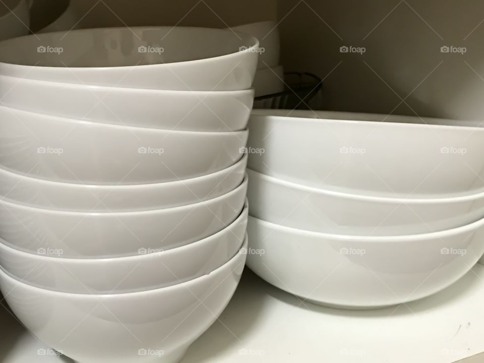 Stack of white bowls in cupboard 