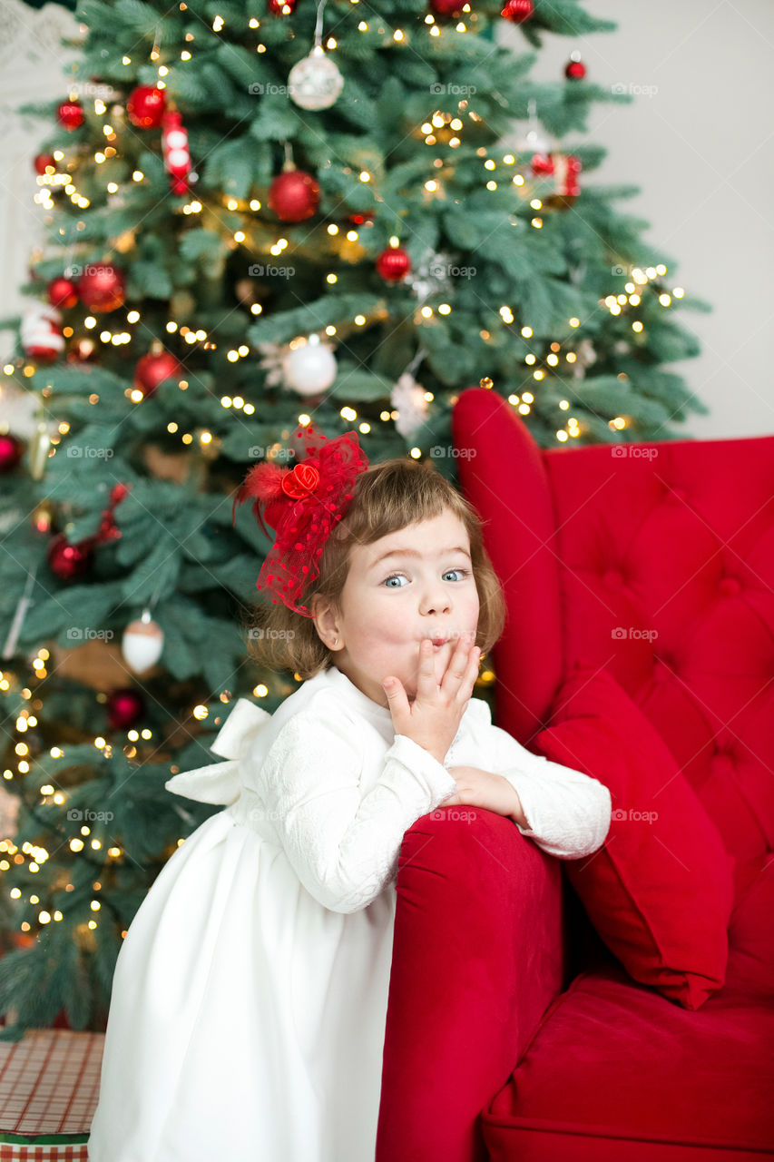 Cute girl standing in front of christmas tree
