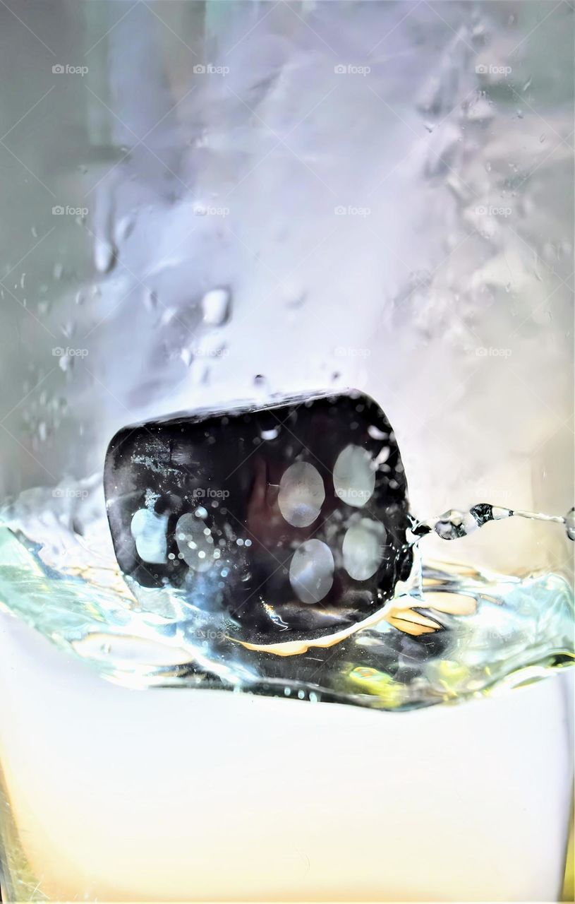 bright picture with black dice showing number 1 and 4 splashing in clear water