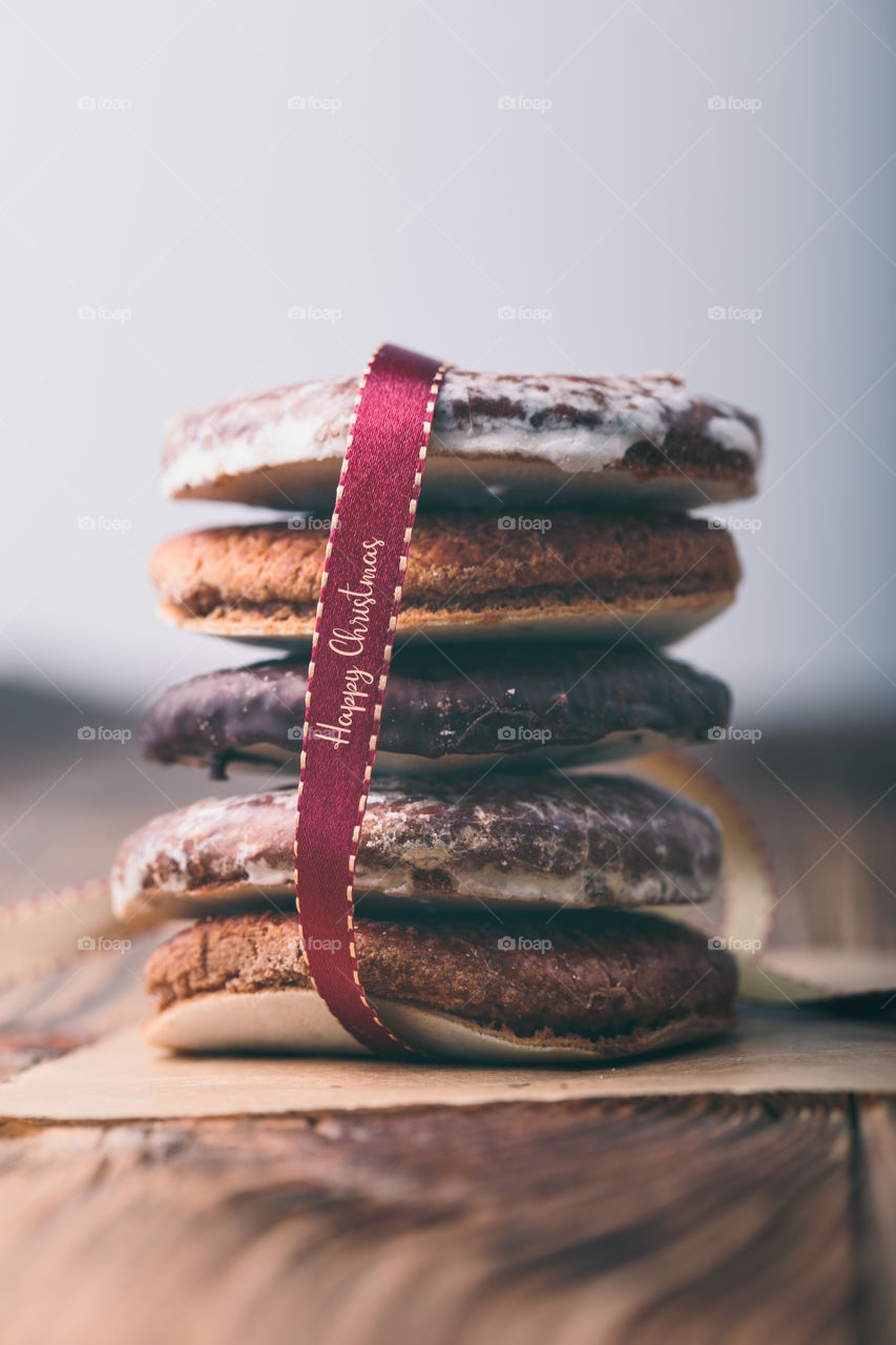 A few gingerbread cookies wrapped in red ribbon Happy Christmas on wooden table. Plain background. Portrait orientation