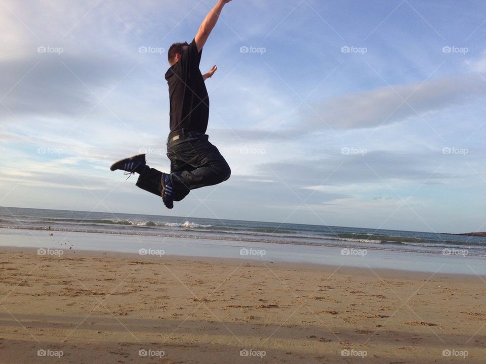 Boy/ man jumping high in the air on the beach