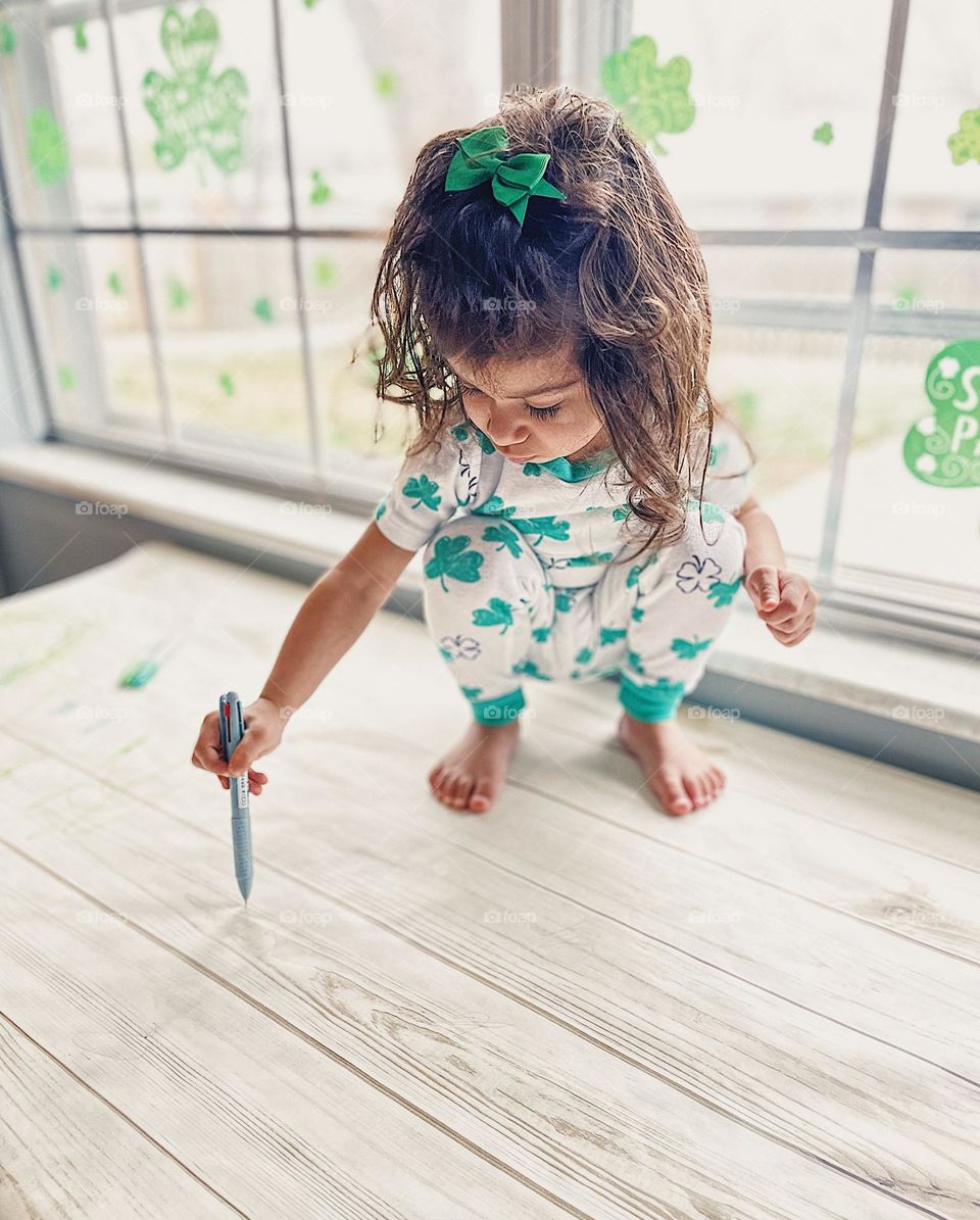 Young child creates art, getting creative with pens, toddler girl drawing on table, making art with mommy, young girl makes an art project, young girl wears clover outfit, tiny human makes art with pens and markers, drawing circles on paper