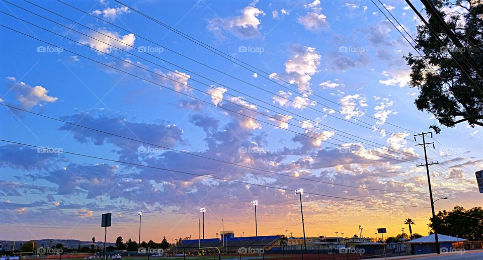 Stadium Lights at Sunset. Stadium Lights come on while the high school marching band prepares to practice for the gsme.