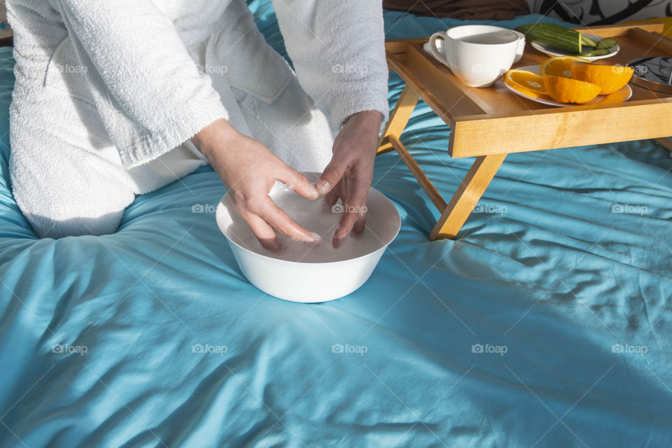 A man at home takes care of himself and does a manicure at home on a blue background and with orange.