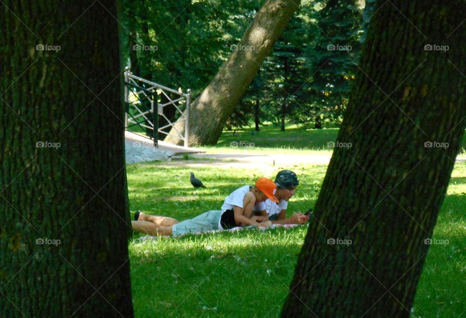 Father and son rest in the park on a green gras