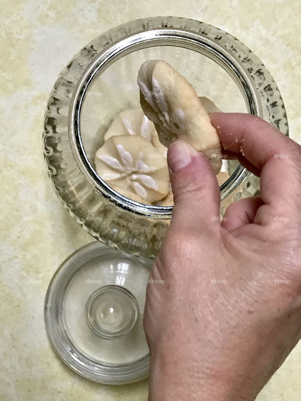 Persons hand taking a cookie from the cookie jar