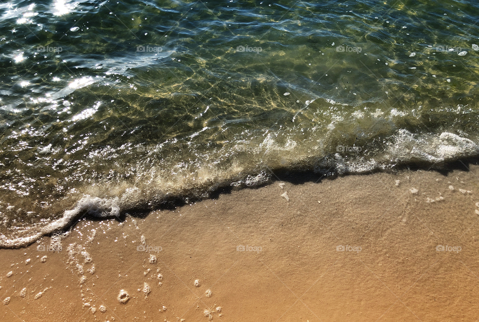 The roar of ocean waves in constant motion against the golden shore.