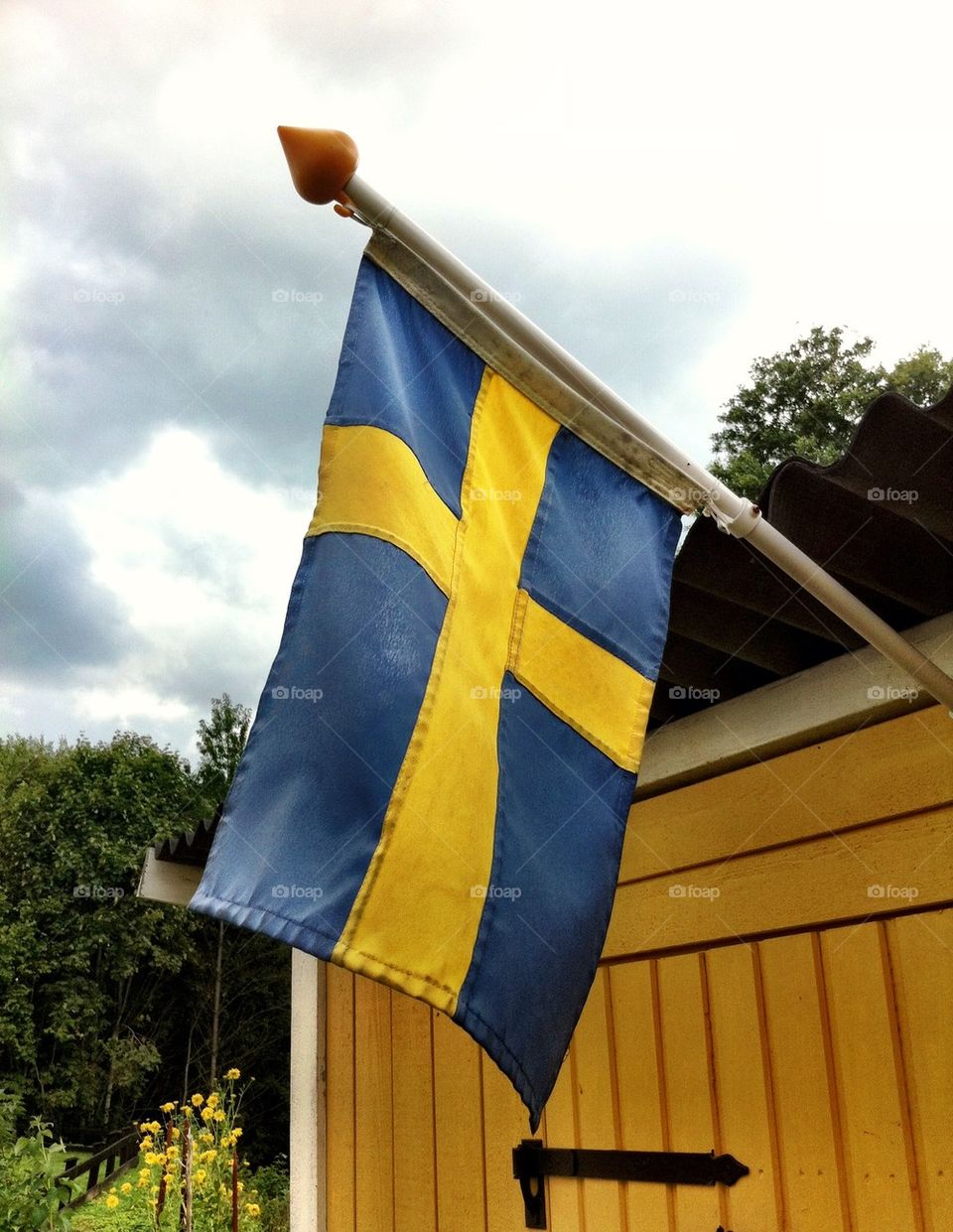 Swedish flag on yellow wooden building.