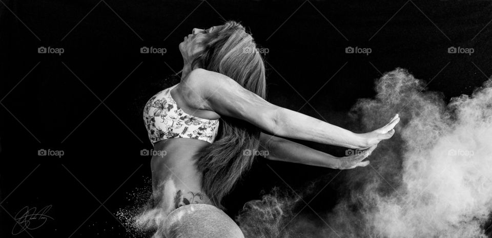 Woman dusting powder on black background