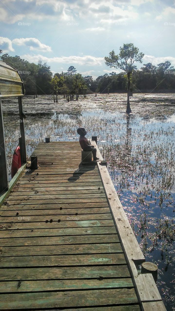 Little cement boy sitting on the Bayou Dock