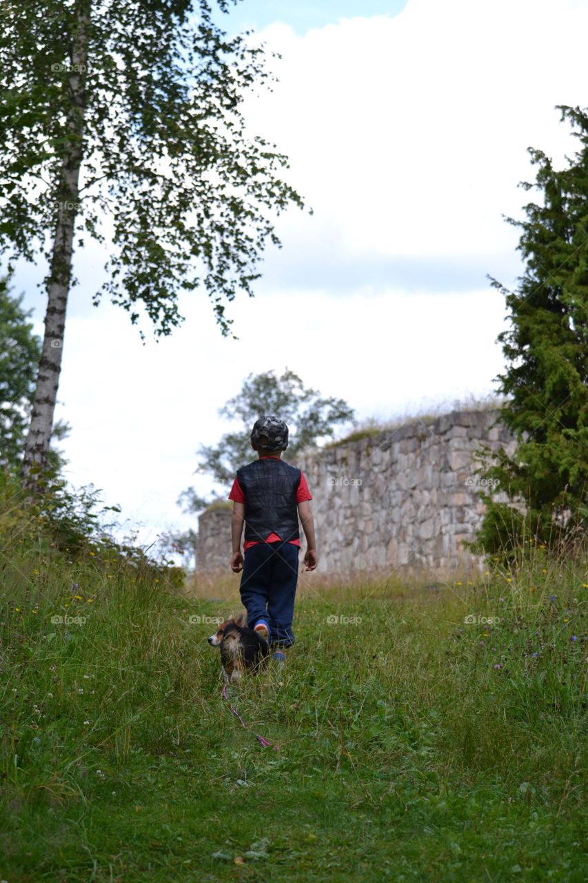 Boy and a pup. Boy walking with a puppy running after him