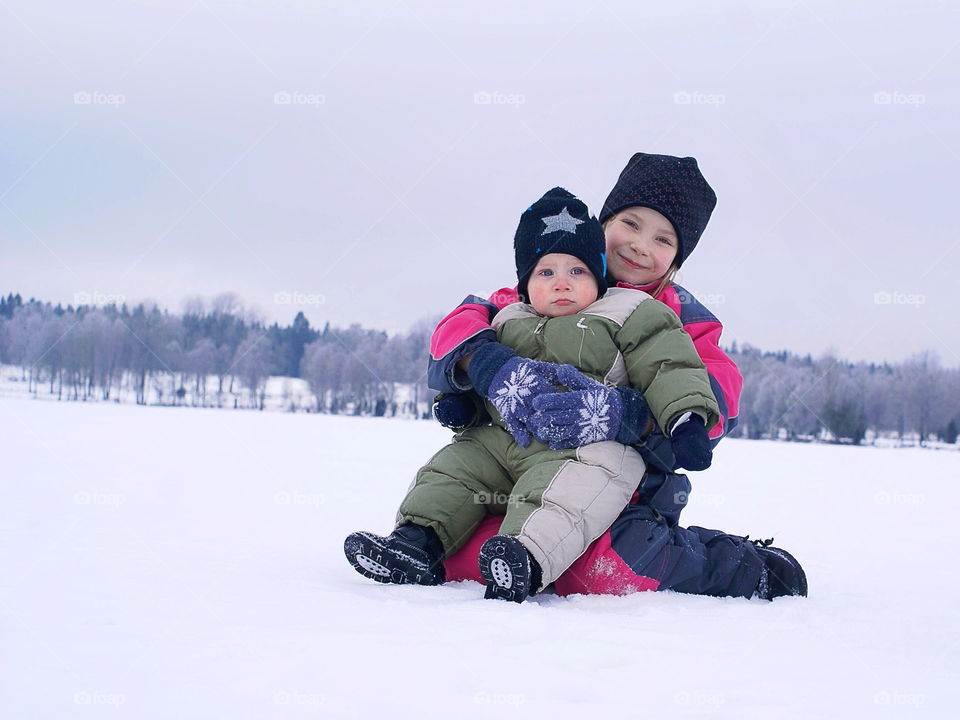 Two children sitting in the snow