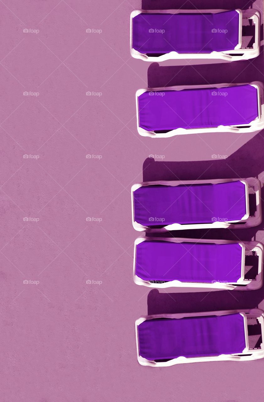 From an incredibly high point of view 26 stories up poolside beach chairs of the violet purple spectrum flat lay perfectly.
